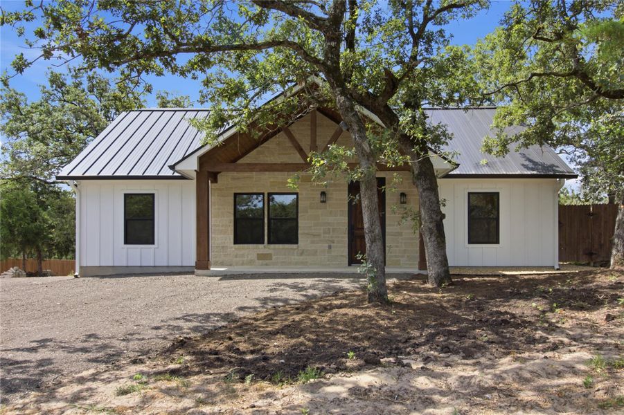 A charming blend of white board-and-batten siding with stone accents creates a welcoming A charming blend of white board-and-batten siding with stone accents creates a welcoming
