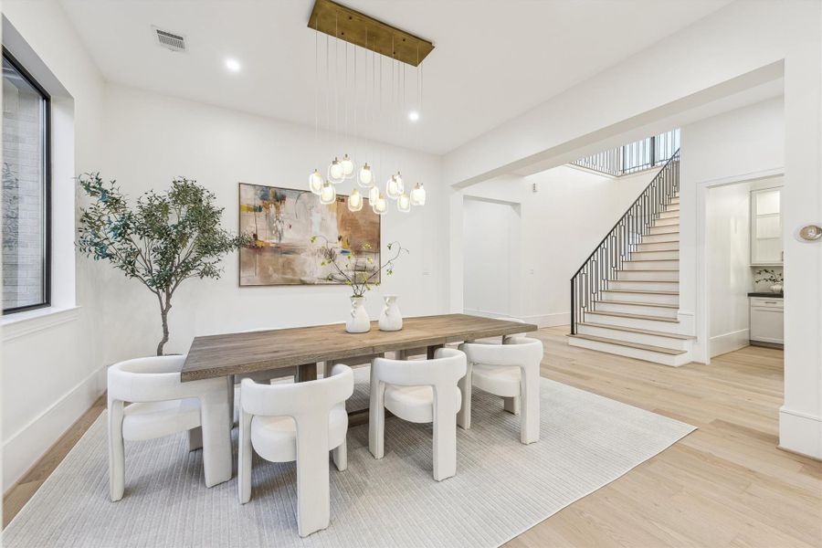 Elgant dining room illuminated by a modern chandelier and recessed lighting.