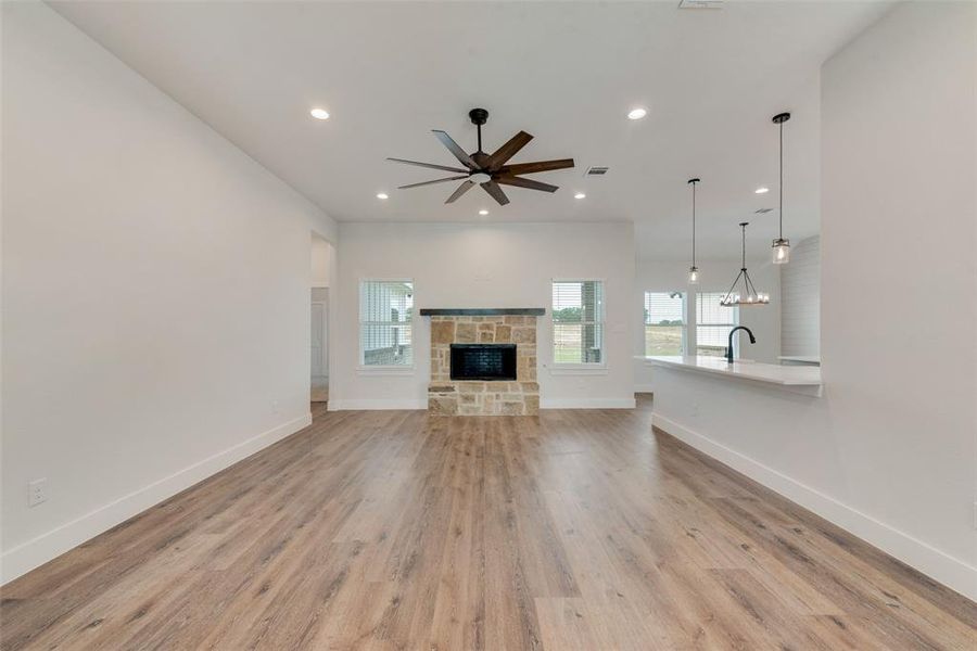 Unfurnished living room featuring light hardwood / wood-style flooring, a fireplace, and ceiling fan