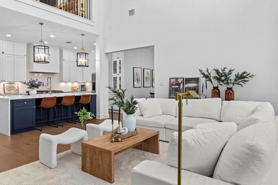 Living room with an inviting chandelier, a towering ceiling, sink, and light hardwood / wood-style floors