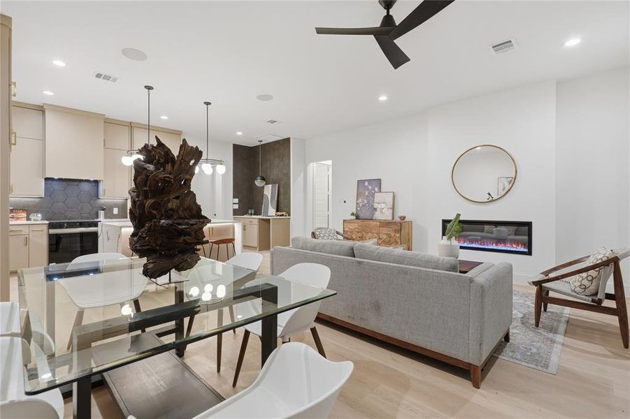 Open-concept living space featuring wood-finish flooring, a linear electric fireplace, and a contemporary ceiling fan