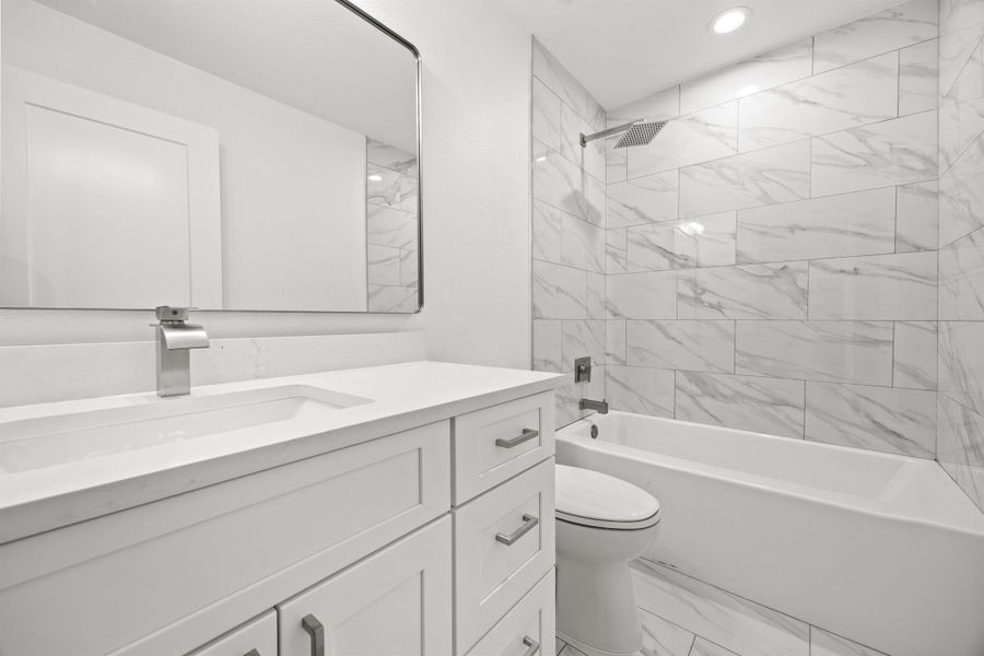 Full bath featuring shower / bath combination, vanity, light marble finish flooring, and recessed lighting