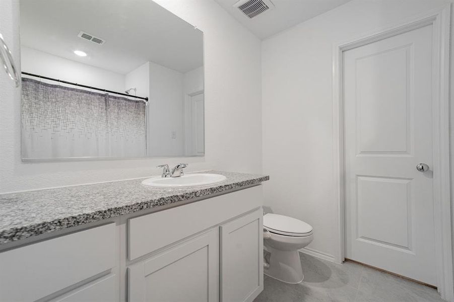 Bathroom featuring vanity, curtained shower, and light tile patterned flooring