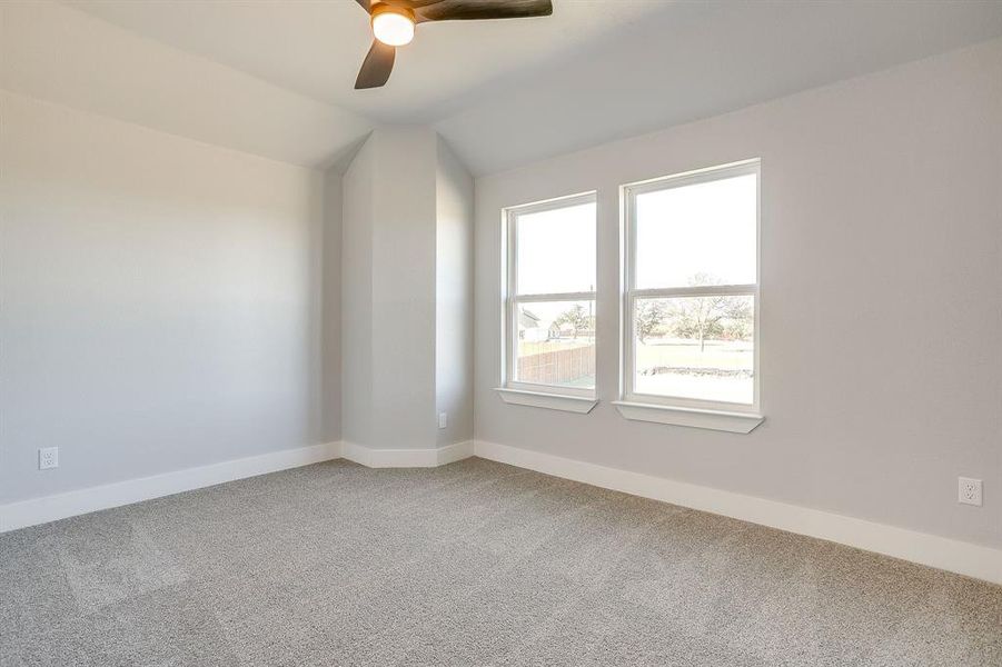 Carpeted empty room with lofted ceiling and a ceiling fan