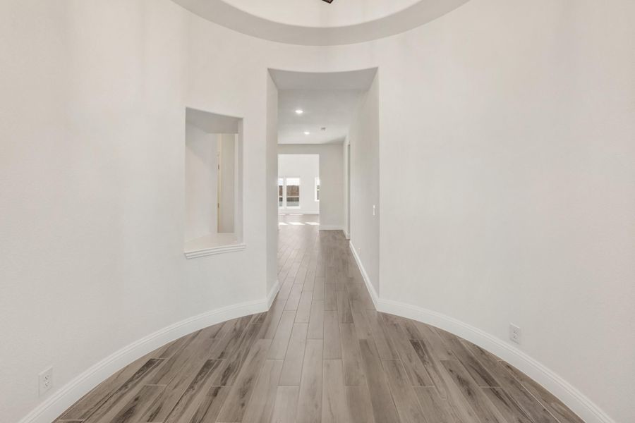 Curved entryway foyer with round ceiling detail, wood-look tile floors, and long hallway leading to main living area Curved entryway foyer with round ceiling detail, wood-look tile floors, and long hallway leading to main living area