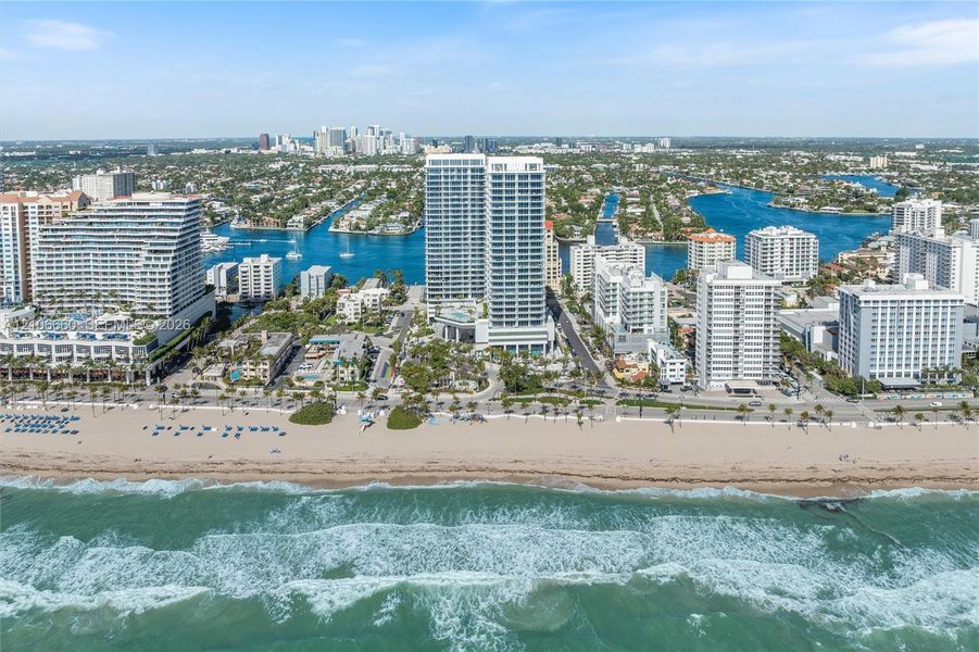 Aerial perspective of a coastal high-rise property featuring direct beach access, proximity to the Atlantic Ocean, and established waterfront surroundings