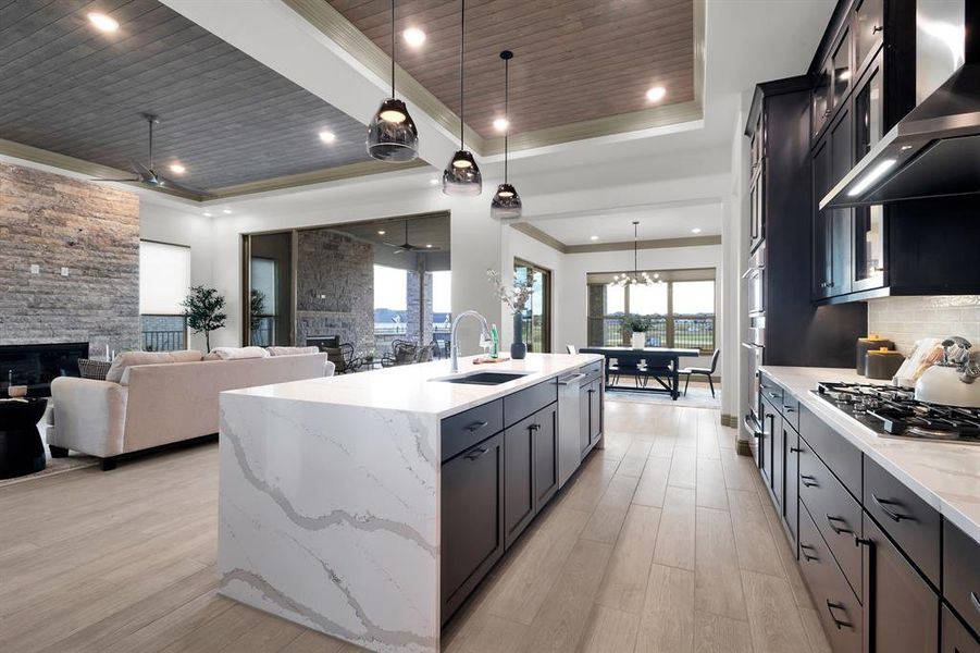 Kitchen with a fireplace, light stone counters, pendant lighting, dark cabinets, and wood ceiling