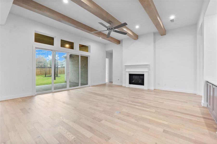 Family Room Adorned with Ceiling Beams, Gas Fireplace, Engineered Hardwood Flooring and Slider Doors to the Covered Rear Patio.