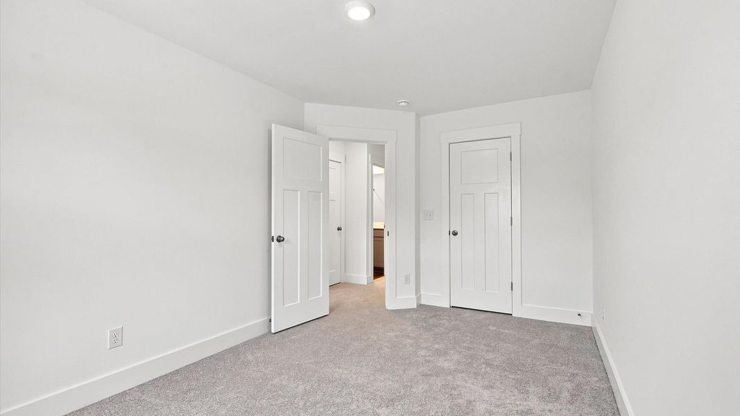 Notable secondary bedroom offering cozy carpeted flooring and a stylish walk-in closet by DRB Homes