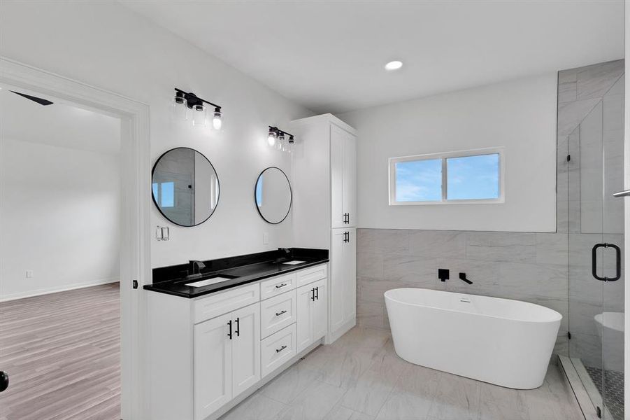 Bathroom featuring a double vanity with black countertops, round mirrors, and overhead lighting