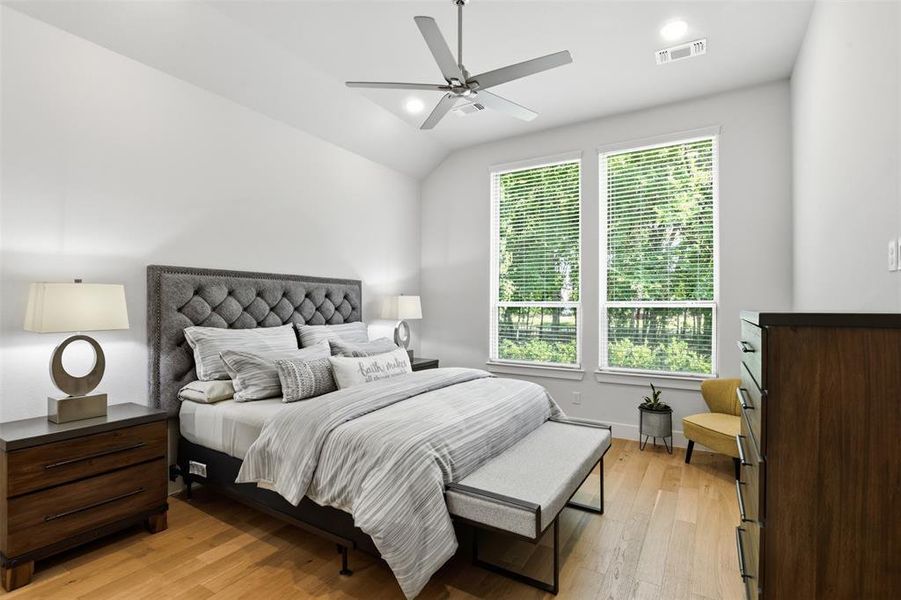 Spacious bedroom featuring wood-finish flooring and a vaulted ceiling Spacious bedroom featuring wood-finish flooring and a vaulted ceiling