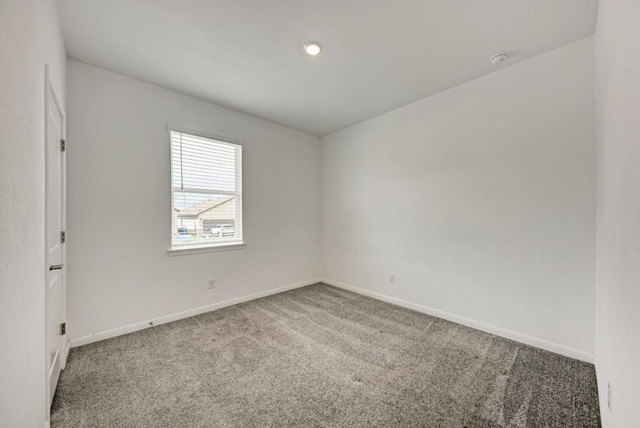 A well-lit bedroom with plush carpeting, offering a neutral canvas for personalization.
