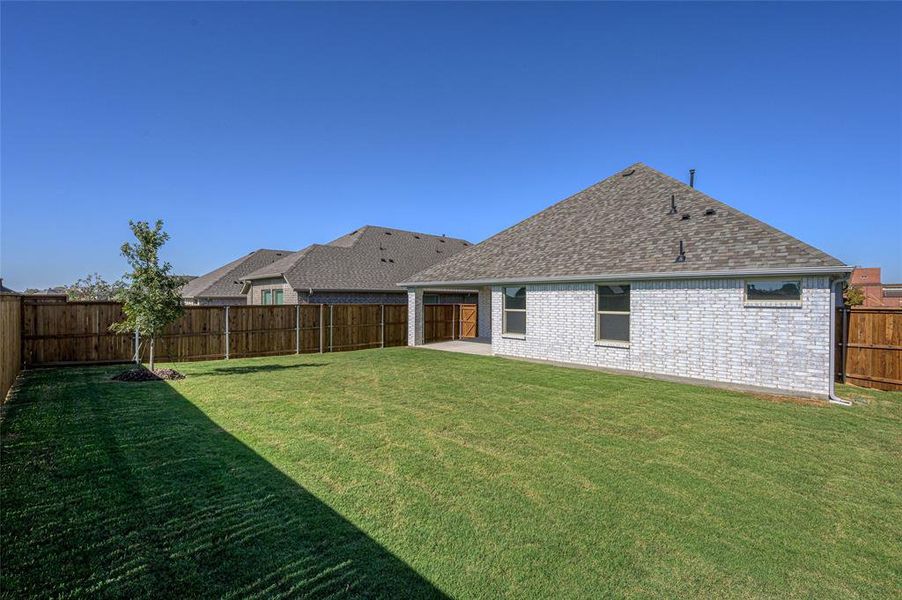 Rear view of house featuring roof with shingles, a patio, brick siding, and a fenced backyard