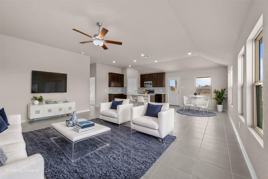 An open concept living area seamlessly flows into the kitchen and dining spaces, illuminated by recessed lighting and a ceiling fan.