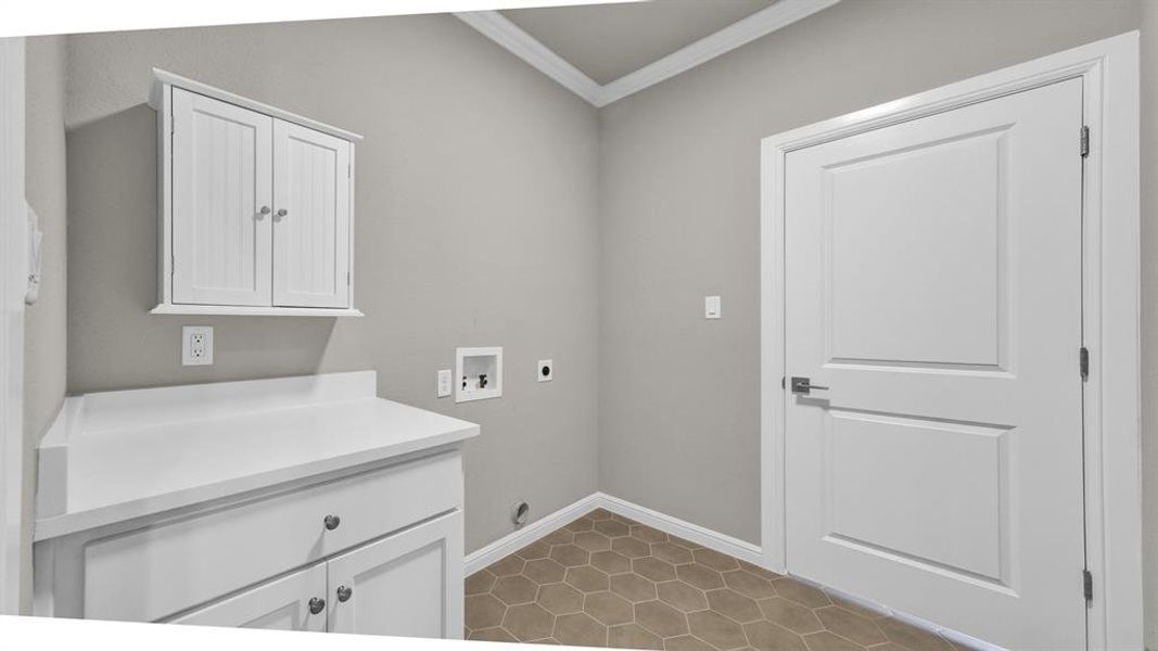 Laundry area featuring hookup for a washing machine, crown molding, hookup for an electric dryer, light tile patterned flooring, and cabinets