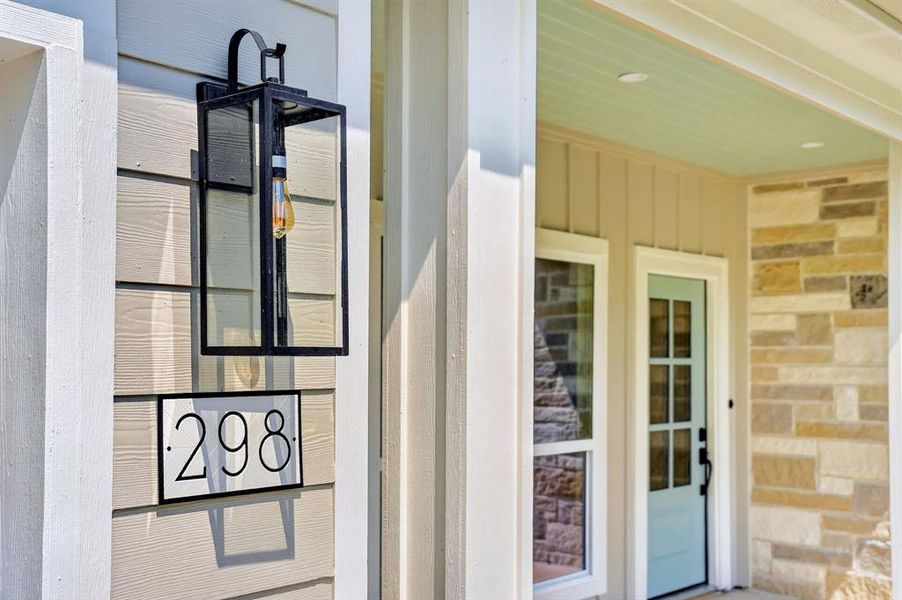 Exterior facade featuring horizontal siding, a contemporary house number plaque, and a black framed lantern-style sconce