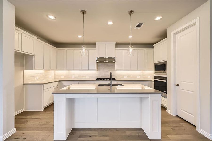 Kitchen with white cabinets, stainless steel appliances, and an island with sink