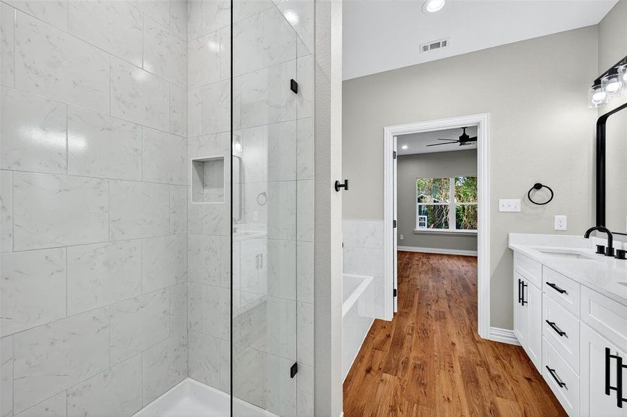 Full bathroom featuring a freestanding tub, double vanity, light wood-style floors, a shower stall, and recessed lighting Full bathroom featuring a freestanding tub, double vanity, light wood-style floors, a shower stall, and recessed lighting