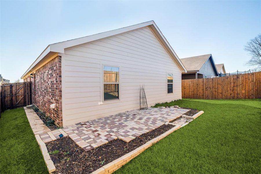 Rear view of property with a yard, brick siding, a patio, and a fenced backyard