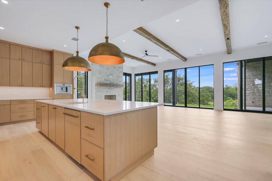 An open-concept living space features light wood flooring, a fireplace, and large windows with outdoor views.