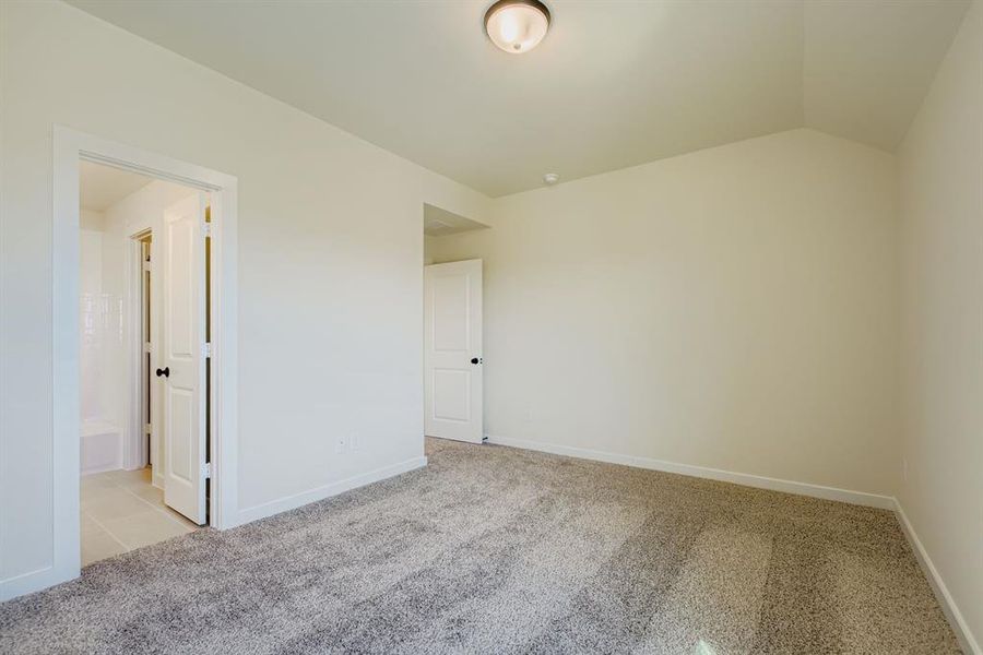 Unfurnished bedroom featuring carpet flooring and lofted ceiling