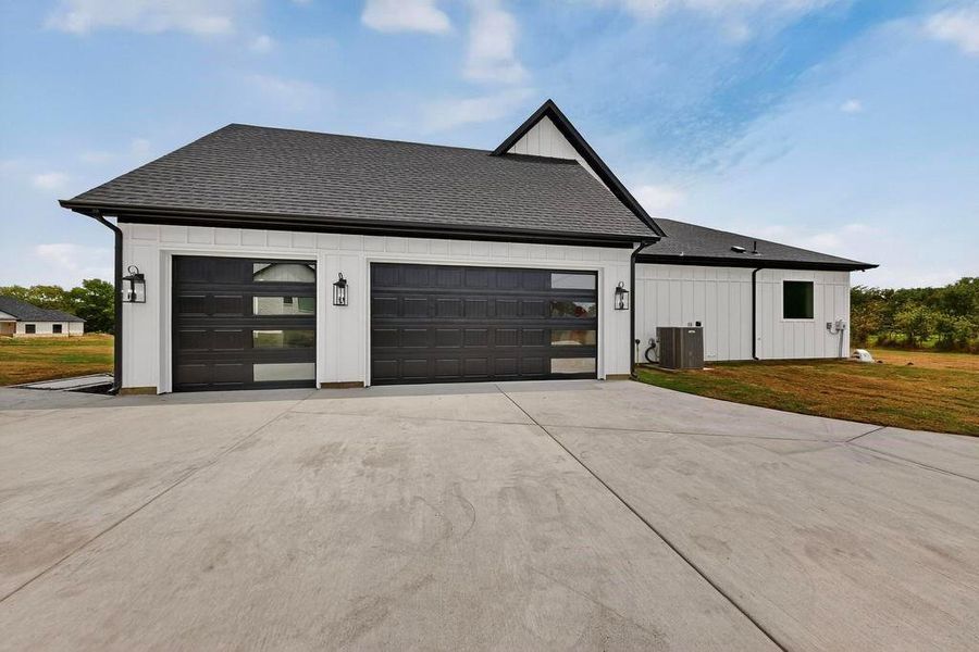 View of home's exterior featuring roof with shingles, driveway, a yard, and a garage View of home's exterior featuring roof with shingles, driveway, a yard, and a garage