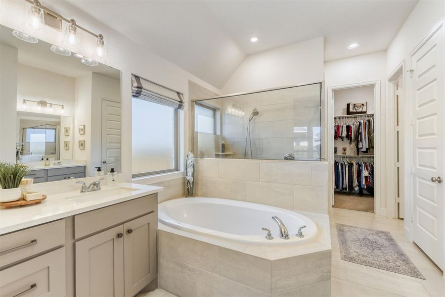 Bathroom with a garden tub, vanity, a walk in closet, a stall shower, and light tile patterned flooring