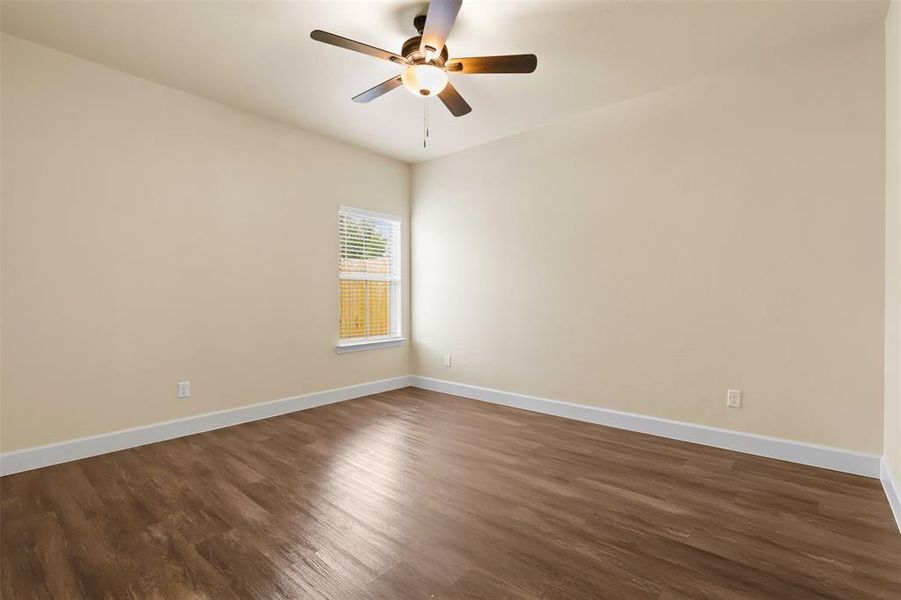 Empty room featuring dark wood-type flooring and ceiling fan