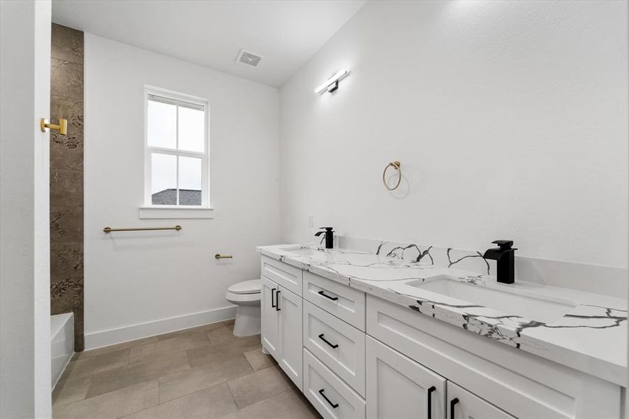 The secondary bathroom features beautifully crafted custom cabinetry, a luxurious 2-in-1 tub and shower combo, dual sinks with elegant quartz countertops, and plenty of storage for linens and everyday products.