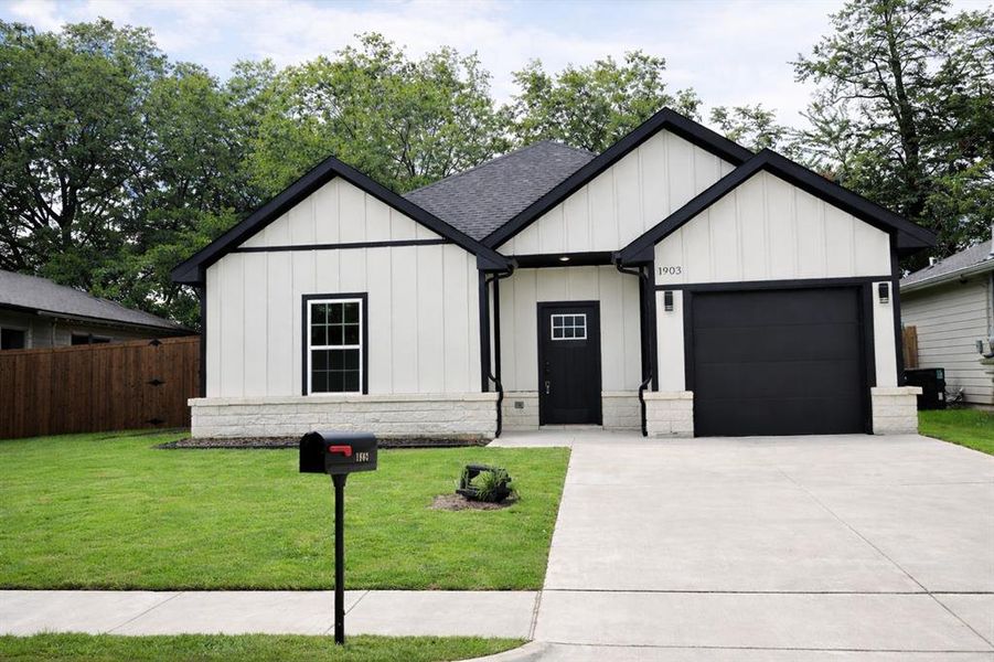 Modern inspired farmhouse with a garage, board and batten siding, concrete driveway, and a shingled roof