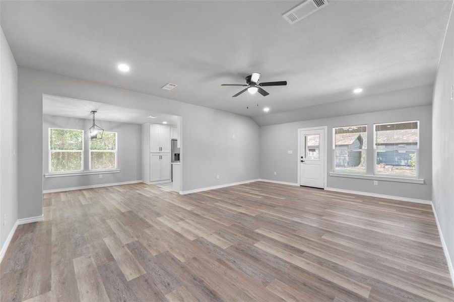 Spacious interior with wood-finish flooring, recessed lighting, and a modern ceiling fan Spacious interior with wood-finish flooring, recessed lighting, and a modern ceiling fan