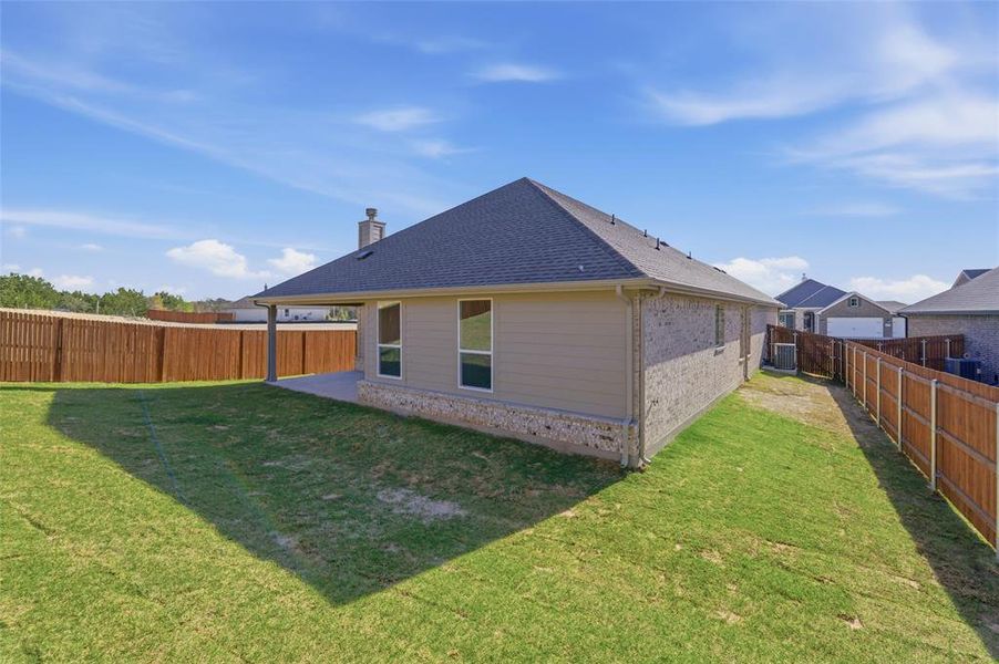 Rear view of property featuring brick siding, a patio area, a fenced backyard, roof with shingles, and a chimney