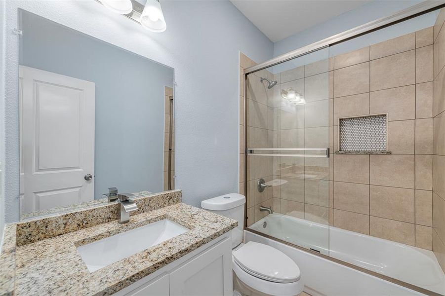 Full bathroom with vanity, toilet, and shower / bath combination with glass door