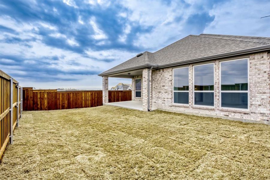 Back of house featuring brick siding, a shingled roof, a patio area, and a fenced backyard