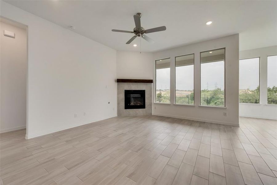 Unfurnished living room featuring a fireplace, light wood-type flooring, and ceiling fan