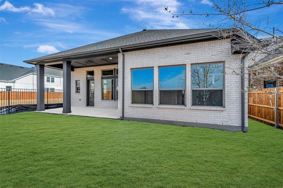 Rear view of house with brick siding, a fenced backyard, a patio, and roof with shingles