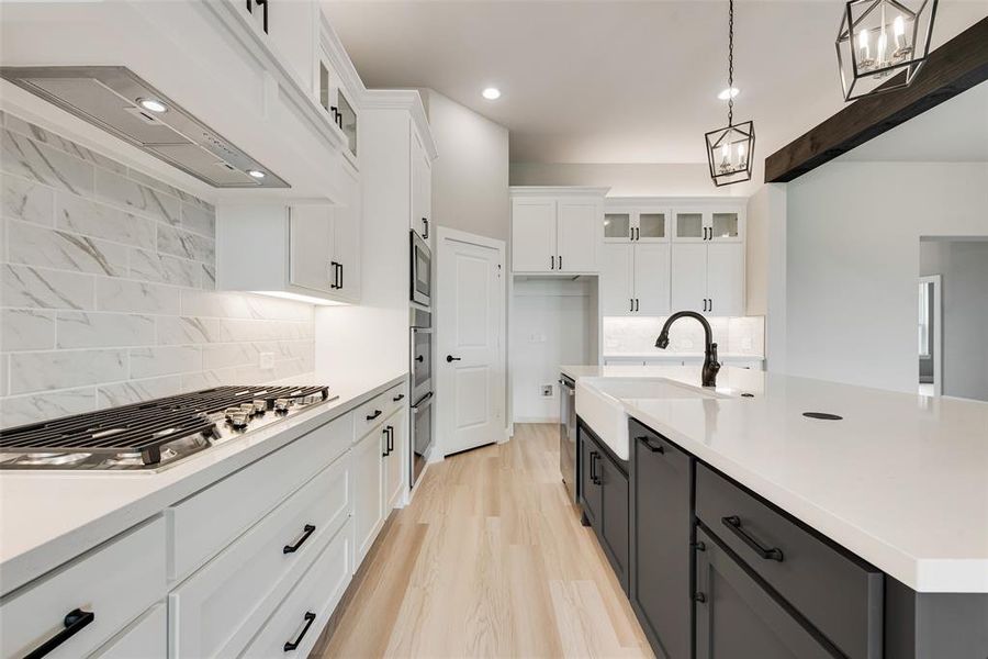 Kitchen featuring tasteful backsplash, decorative light fixtures, white cabinetry, stainless steel appliances, and a notable chandelier