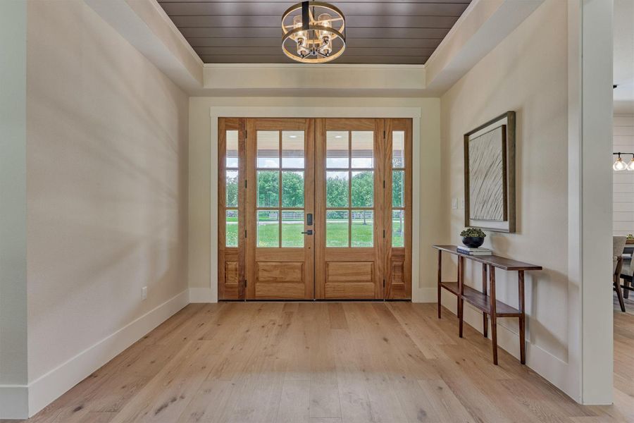A grand entry: 8' double mahogany doors with glass sidelights welcome you home, framed by a stained wood ceiling accent and a smart lock for modern convenience. The view straight through to the backyard sets the tone from the moment you walk in. A grand entry: 8' double mahogany doors with glass sidelights welcome you home, framed by a stained wood ceiling accent and a smart lock for modern convenience. The view straight through to the backyard sets the tone from the moment you walk in.