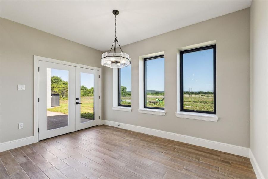 Eat in kitchen area with an inviting chandelier, baseboards, wood look tile floors, and french doors Eat in kitchen area with an inviting chandelier, baseboards, wood look tile floors, and french doors