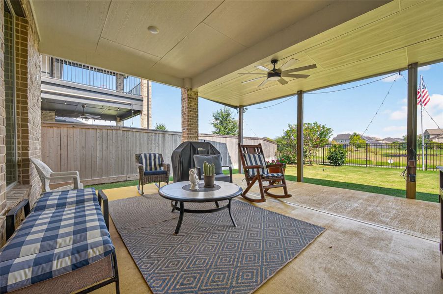 This photo showcases a spacious covered patio with comfortable seating, a ceiling fan, and a grill, overlooking a well-maintained backyard with a view of neighboring homes and a garden. Perfect for outdoor relaxation and entertainment. This photo showcases a spacious covered patio with comfortable seating, a ceiling fan, and a grill, overlooking a well-maintained backyard with a view of neighboring homes and a garden. Perfect for outdoor relaxation and entertainment.