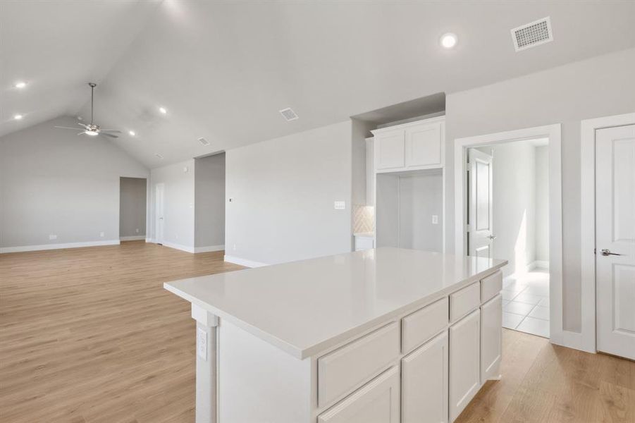 Kitchen with white cabinets, light hardwood / wood-style floors, a kitchen island, and ceiling fan