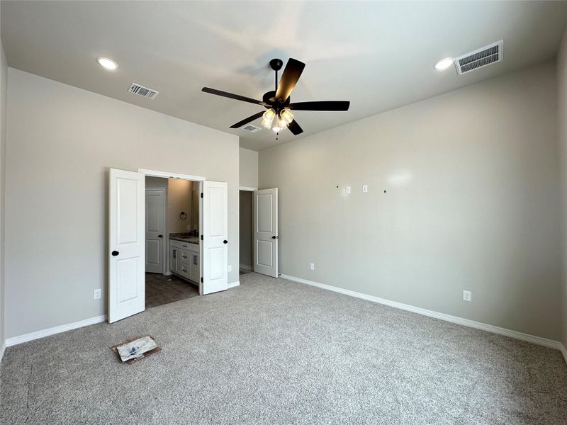 Unfurnished bedroom with light carpet, ensuite bathroom, recessed lighting, and a ceiling fan