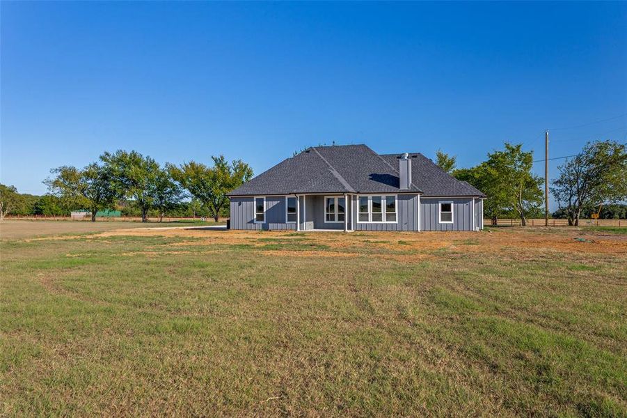 Back of house featuring a lawn, roof with shingles, and a patio area Back of house featuring a lawn, roof with shingles, and a patio area