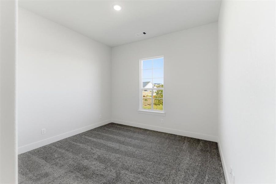 Empty room featuring dark colored carpet and recessed lighting
