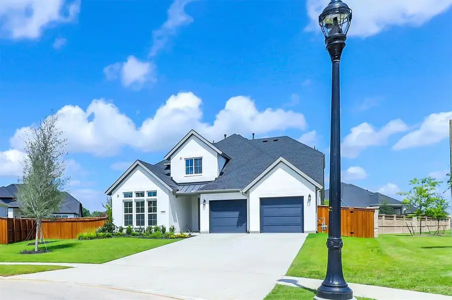 Modern Colonial-style home featuring a crisp white exterior, dark gray roofing, and a two-car garage with dark gray doors Modern Colonial-style home featuring a crisp white exterior, dark gray roofing, and a two-car garage with dark gray doors
