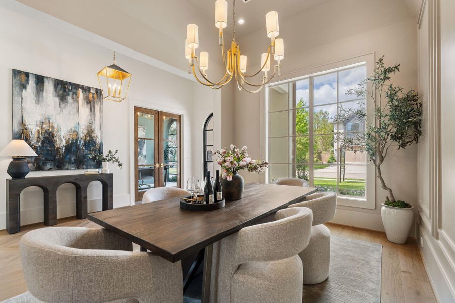 Positioned just off the entry, the formal dining room is framed by oversized windows that fill the space with natural light. High ceilings and a striking chandelier create an elegant setting, complemented by seamless flow into adjacent living areas.