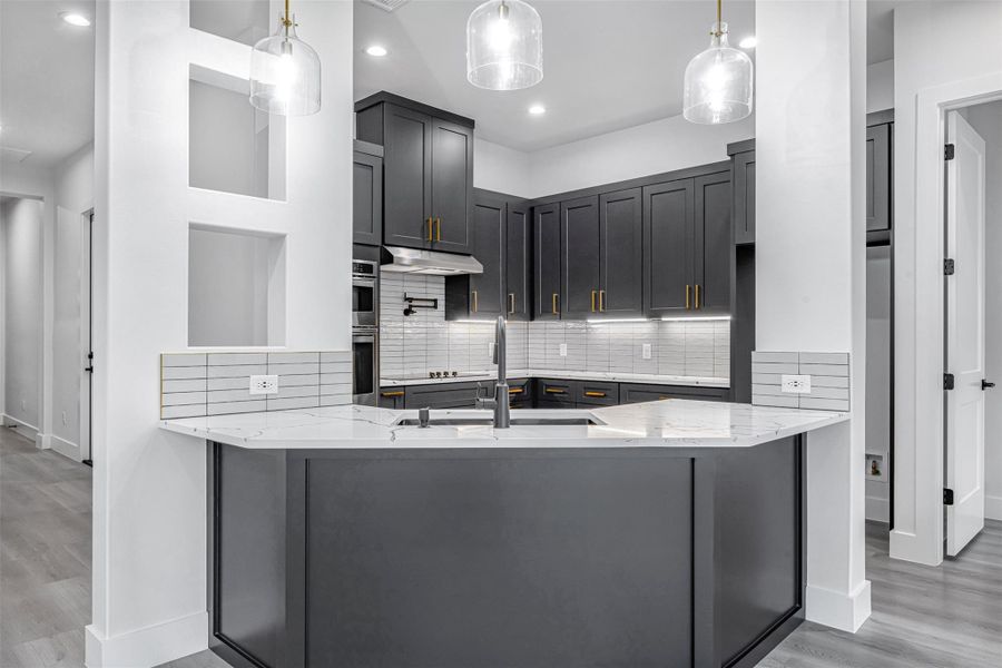Kitchen featuring a sink, light stone countertops, baseboards, under-cabinet range hood, and recessed lighting. Kitchen featuring a sink, light stone countertops, baseboards, under-cabinet range hood, and recessed lighting.