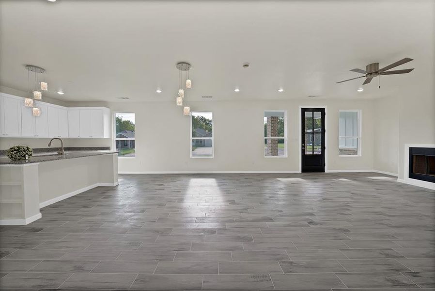 Unfurnished living room with recessed lighting, a ceiling fan, a fireplace, and dark wood-type flooring