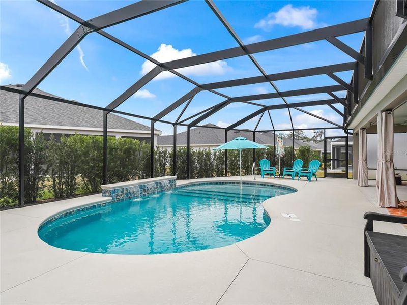 Pool area with expanded patio space, shallow shelf with umbrella, and three waterfalls