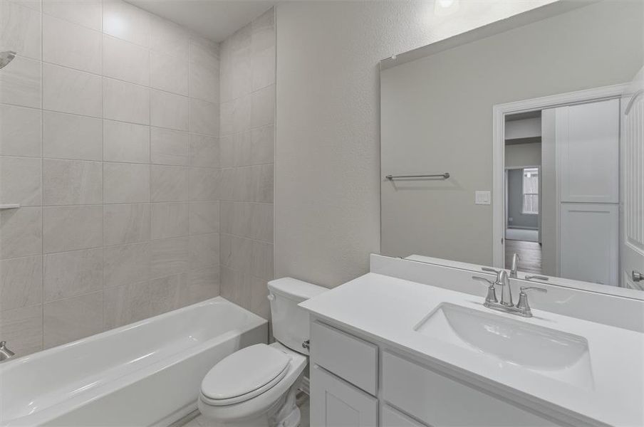 Bathroom featuring a white vanity with an integrated sink, polished chrome faucet, and expansive mirror